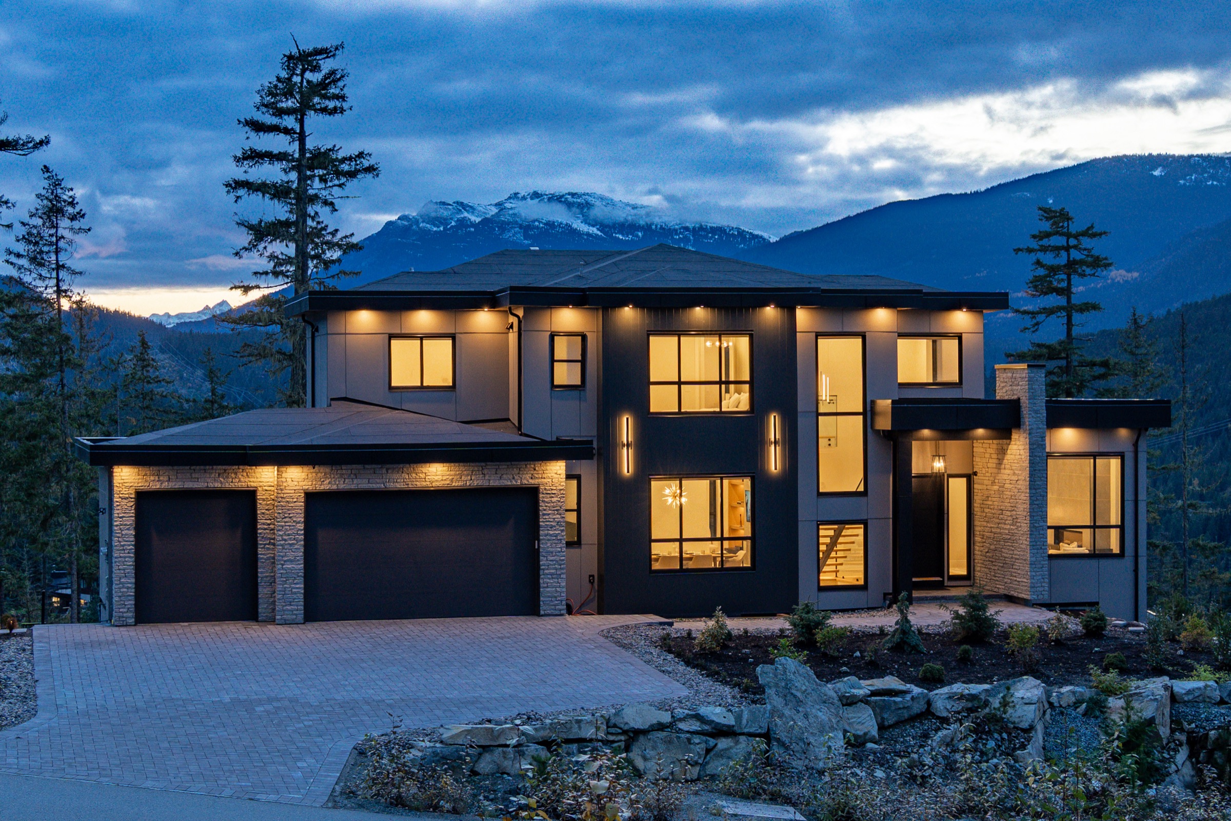 Illuminated luxury home at 9289 Stellar’s Way framed by the mountains at blue hour