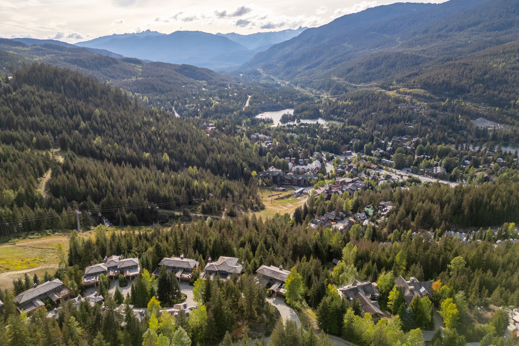Aerial view across Whistler Creekside, lakes, forest, and the Sea to Sky mountains